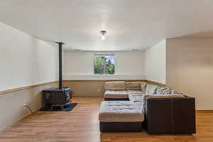 Living area with a wood stove, wood finished floors, and a textured ceiling