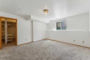 Unfurnished bedroom featuring carpet flooring, a walk in closet, baseboards, and a closet