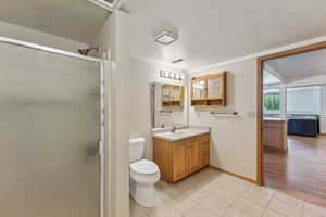 Bathroom featuring tile patterned floors, vanity, a stall shower, toilet, and baseboards