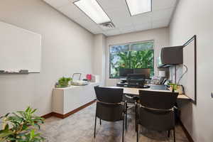 Home office with a drop ceiling and baseboards