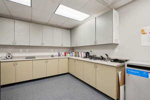 Kitchen featuring light countertops, cream cabinets, a paneled ceiling, and dark speckled floor