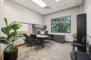 Office space with light carpet, baseboards, and a drop ceiling