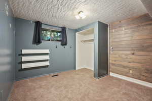 Unfurnished bedroom with carpet, a closet, baseboards, and a textured ceiling