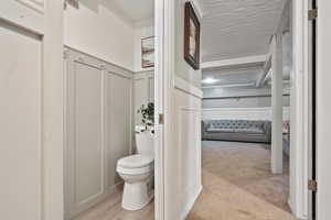 Bathroom featuring a decorative wall, toilet, and wainscoting