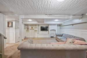Living area with a wainscoted wall and a textured ceiling