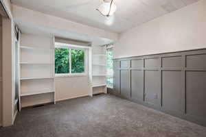 Unfurnished bedroom featuring carpet flooring, a decorative wall, and a wainscoted wall
