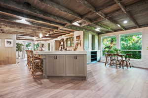 Kitchen with light countertops, gray cabinetry, light wood-style flooring, and wooden walls
