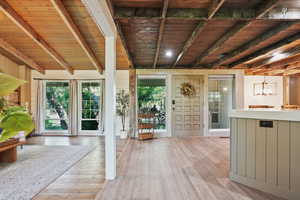 Interior space featuring wood ceiling with exposed beams, healthy amount of natural light, and light wood-style flooring