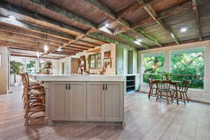 Kitchen with gray cabinets, light countertops, light wood-type flooring, plenty of natural light, and wooden ceiling with exposed beams