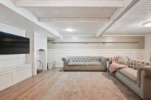 Living room featuring light wood-style floors, a decorative wall, and a wainscoted wall