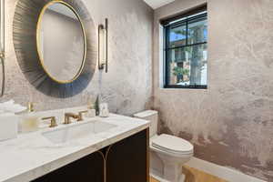 Bathroom with toilet, vanity, and wood finished floors