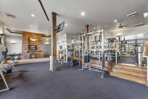 Gym featuring a stone fireplace and recessed lighting