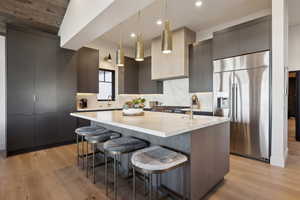 Kitchen featuring stainless steel fridge with ice dispenser, modern cabinets, a sink, an island with sink, and recessed lighting