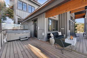 Deck with a hot tub and an outdoor living space with a fire pit