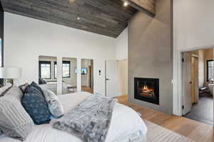 Bedroom with high vaulted ceiling, wood finished floors, a fireplace, and arched walkways