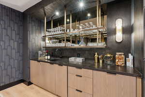 Indoor wet bar featuring wood finished floors and backsplash