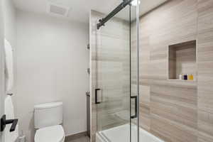 Full bath featuring enclosed tub / shower combo, toilet, and a sauna