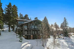 Snow covered rear of property featuring a balcony