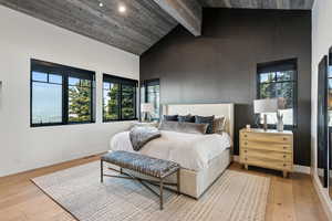 Bedroom with high vaulted ceiling, light wood finished floors, multiple windows, baseboards, and recessed lighting