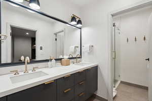 Full bathroom with double vanity, a stall shower, baseboards, and tile patterned flooring