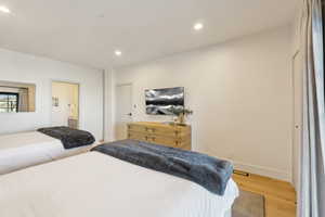 Bedroom with light wood finished floors, recessed lighting, baseboards, and connected bathroom