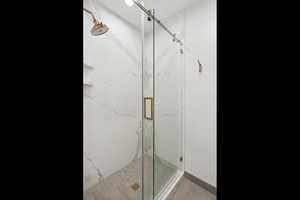 Full bath with a marble finish shower