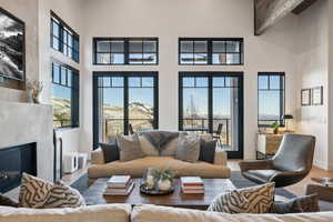 Living room featuring a high ceiling, a fireplace, beamed ceiling, and wood finished floors