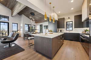 Kitchen featuring a sink, modern cabinets, a center island with sink, pendant lighting, and light wood finished floors