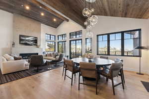 Dining space featuring high vaulted ceiling, recessed lighting, light wood-style flooring, wooden ceiling with exposed beams, and baseboards