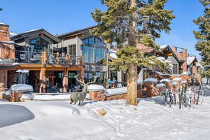 Snow covered back of property with a wooden deck