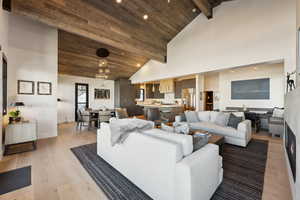Living area featuring high vaulted ceiling, light wood-type flooring, recessed lighting, wood ceiling with exposed beams, and baseboards