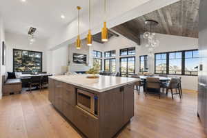Kitchen featuring open floor plan, modern cabinets, stainless steel microwave, light wood-style flooring, and recessed lighting
