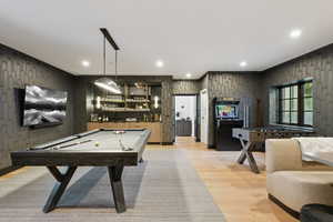 Recreation room with light wood-style flooring, pool table, recessed lighting, and bar