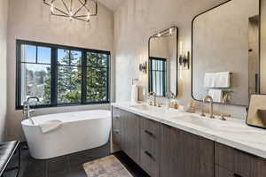 Bathroom with double vanity, a soaking tub, and a chandelier