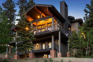 Rear view of house featuring a balcony, board and batten siding, and a chimney