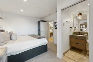 Bedroom featuring a sink, recessed lighting, ensuite bathroom, light colored carpet, and baseboards
