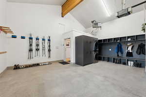 Garage with stacked washer and clothes dryer, a garage door opener, a heating unit, and baseboards