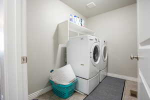 Laundry area with washing machine and clothes dryer, light tile patterned floors, and baseboards