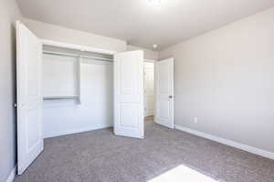 Unfurnished bedroom featuring carpet floors, baseboards, and a closet