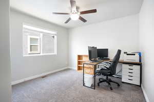Carpeted office space featuring ceiling fan and baseboards