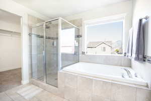 Bathroom featuring a shower stall, a garden tub, tile patterned floors, and a walk in closet