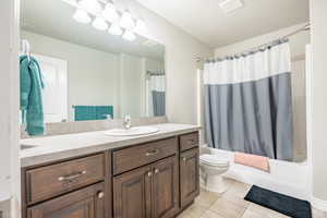 Full bath featuring vanity, tile patterned floors, toilet, and shower / bath combo with shower curtain