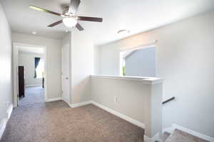 Empty room with carpet flooring, plenty of natural light, a ceiling fan, and baseboards