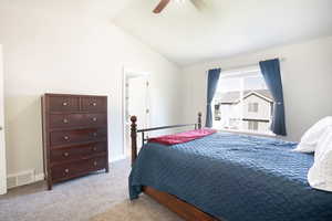 Bedroom featuring vaulted ceiling, light carpet, and ceiling fan
