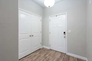 Foyer entrance with light wood-style floors and baseboards