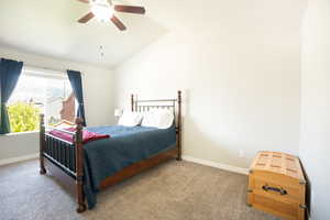 Carpeted bedroom with lofted ceiling, baseboards, and a ceiling fan