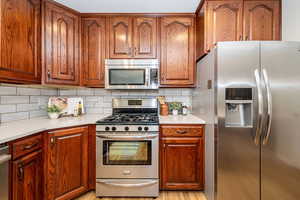 Kitchen with appliances with stainless steel finishes, tasteful backsplash, and light countertops