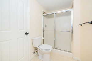 Bathroom with an enclosed shower, toilet, and baseboards