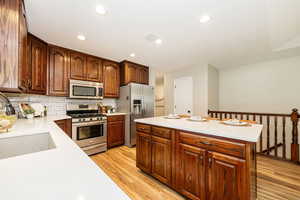 Kitchen with stainless steel appliances, a sink, light countertops, light wood-style floors, and recessed lighting