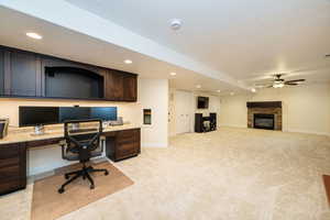Office space featuring built in study area, light carpet, recessed lighting, ceiling fan, and a fireplace